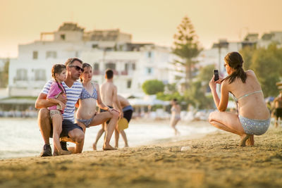 Woman photographing with people sitting against sky