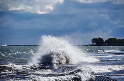 Waves breaking against sea against sky