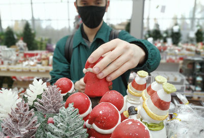 Midsection of man wearing mask holding souvenir at store