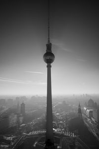 Communications tower in city against sky