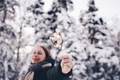 Woman holding heart shape sparkler in winter