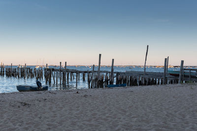 Wooden posts on beach against clear sky