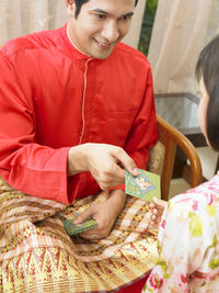 Father giving envelope to daughter at home