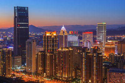 Illuminated modern buildings in city against sky