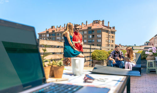 Colleagues talking in a coffee break on rooftop with laptop in foreground