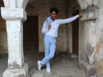 Full length portrait of smiling standing against stone wall