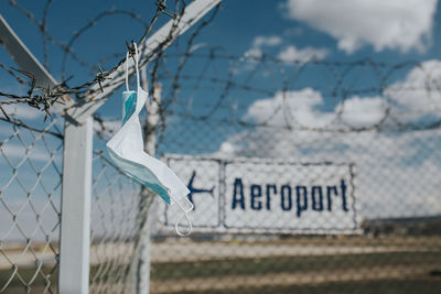 Close-up of text on fence against sky