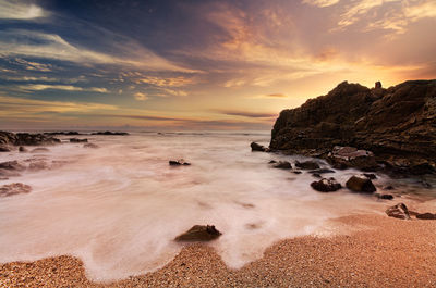 Scenic view of sea against dramatic sky during sunset