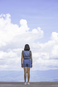 Rear view of woman standing on land against sky