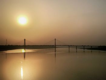 Bridge over water against sky during sunset