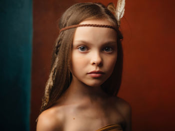 Close-up portrait of a young woman against wall