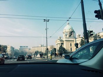 Cars on street in city against sky