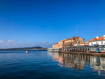 Buildings at waterfront against blue sky