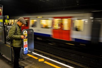 Young man photographing speeding train at railroad station