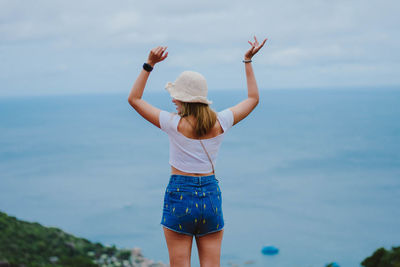 Rear view of woman standing in sea against sky