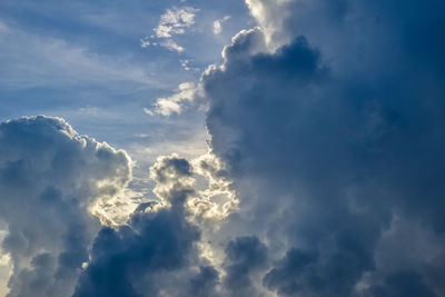 Low angle view of sunlight streaming through clouds