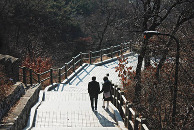 Rear view of people walking on footbridge