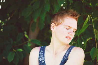 Young woman against tree