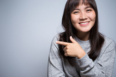 Smiling young woman against gray background