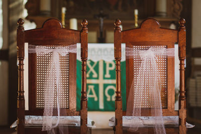 Close-up of empty handcrafted wooden chairs in front of altar with christian symbols 