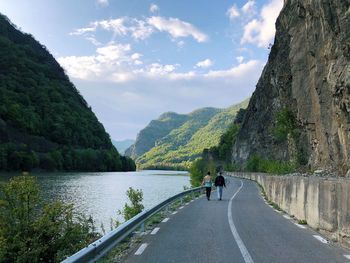 Rear view of people on road by mountain against sky