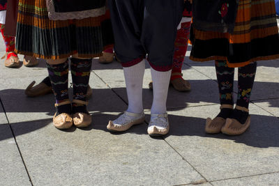 Low section of people in traditional clothing standing on footpath