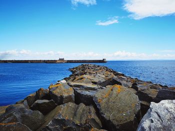 Rocks by sea against blue sky