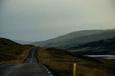 Road leading towards mountains against clear sky