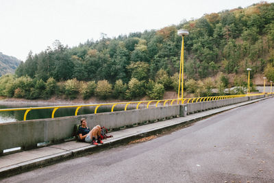 People on bridge by road against sky