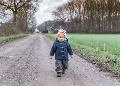 Cute girl walking on dirt road during winter