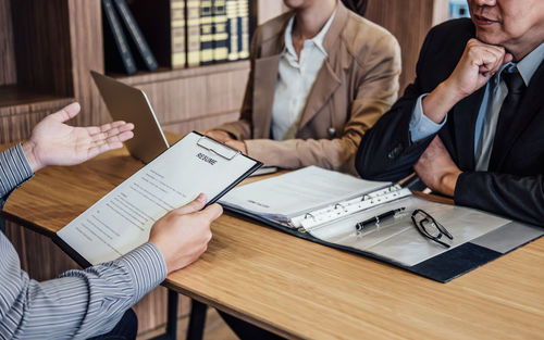 Midsection of man giving interview of business people in office