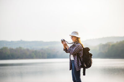 Female tourists happily taking photos of the natural surroundings around the reservoir.