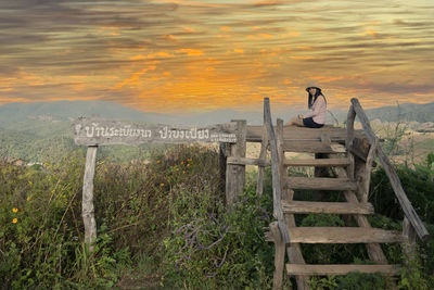 Panoramic view of people sitting on land against sky during sunset