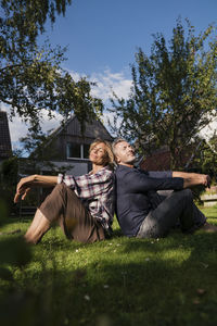 Man and woman sitting with eyes closed on grass in back yard