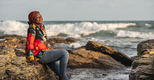 African woman sitting on the beach cliffs at sunset in accra ghana west africa