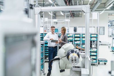 Businesswoman and manwith tablet talking in a modern factory