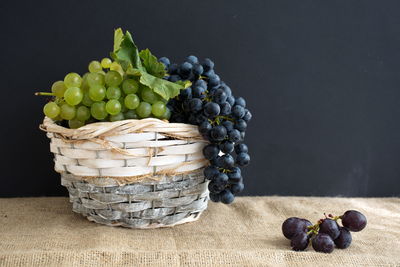 Close-up of grapes in basket on table against black background