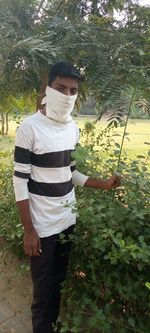 Man standing by plants against trees