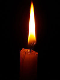 Close-up of illuminated candle against black background