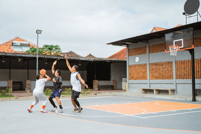 Men playing basketball court against sky