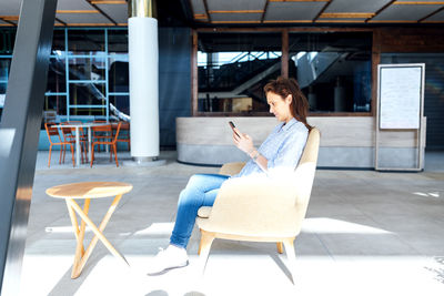 Woman using mobile phone while sitting on chair
