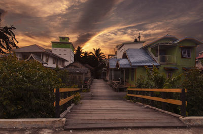 Footpath amidst buildings against sky at sunset