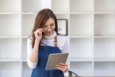 Young woman using digital tablet while standing in library