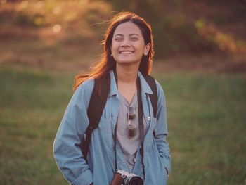 Portrait of young woman standing on grassy field