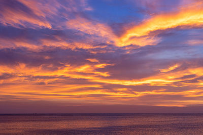 Scenic view of sea against dramatic sky during sunset