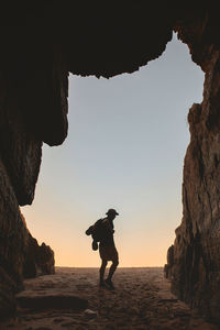 Rear view of man standing on rock formation at sunset