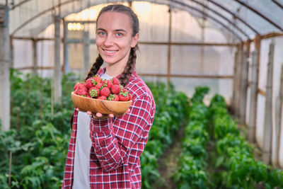 Portrait of young woman standing by plants