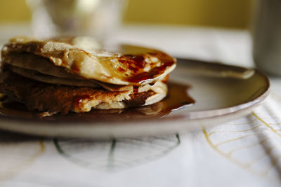 Closeup yummy pancakes with sweet maple syrup placed on plate on table