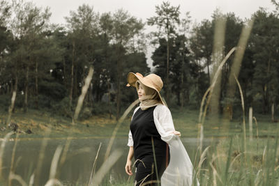 Woman standing by lake against trees