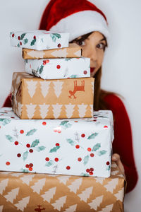 Portrait young woman holding christmas gifts standing against white background